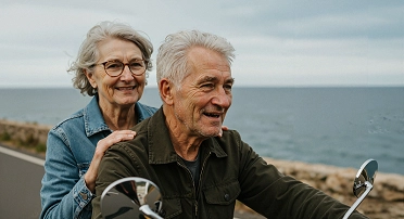 Pareja adulta mayor manejando una motocicleta por la carretera junto al mar, disfrutando la vida tras planificar su retiro con la modalidad 40